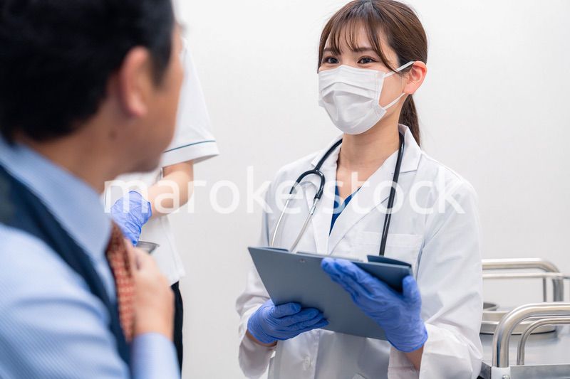 病院で男性患者の問診をする女性医師