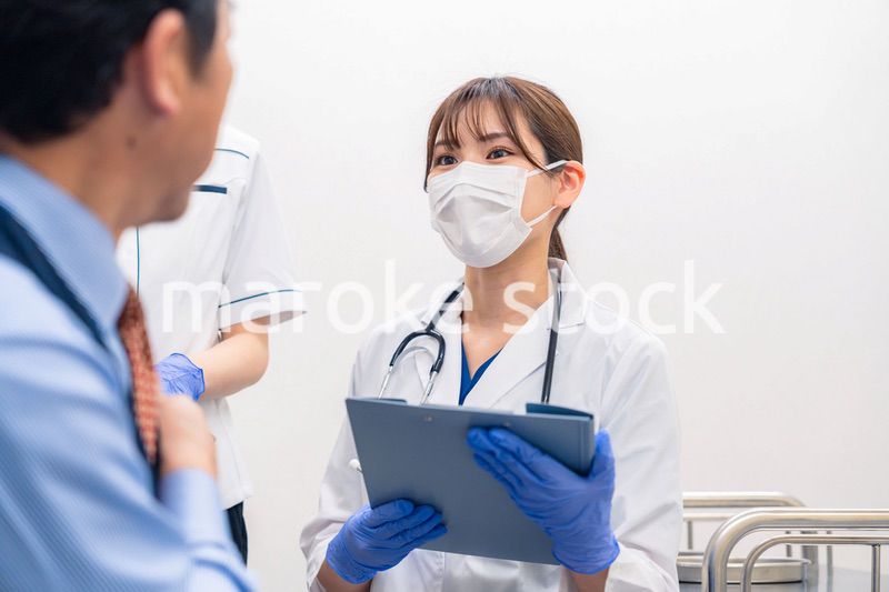病院で男性患者の問診をする女性医師