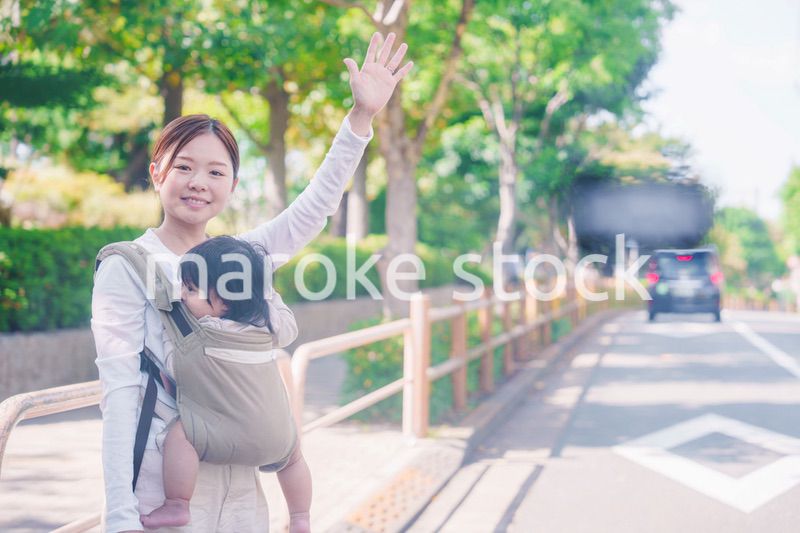 流しのタクシーを止める抱っこ紐をした女性