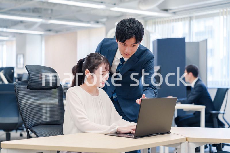 先輩社員から業務を教えてもらう新人の女性