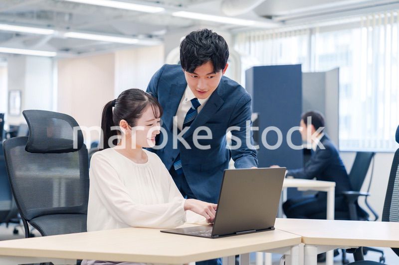 先輩社員から業務を教えてもらう新人の女性