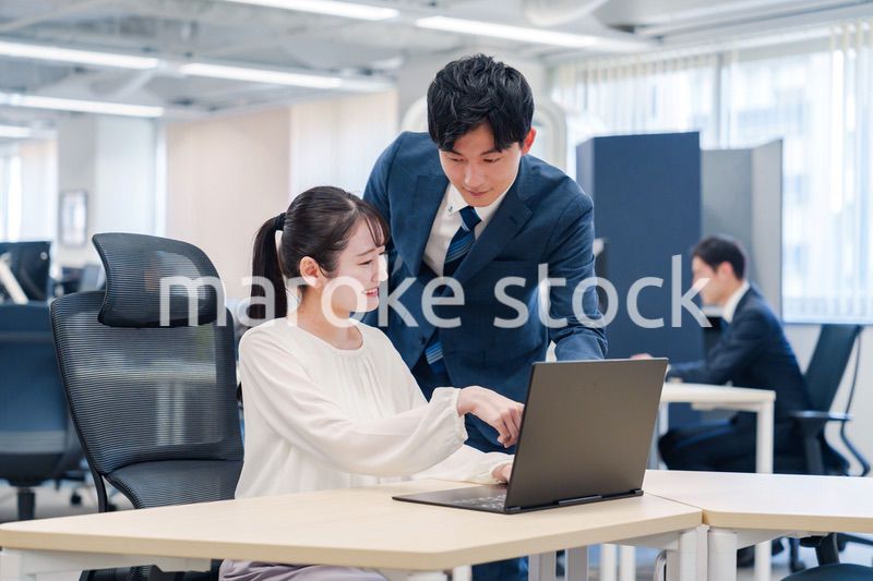 先輩社員から業務を教えてもらう新人の女性