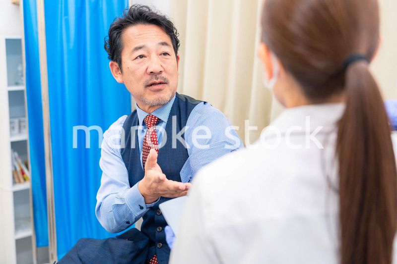 病院で男性患者の問診をする女性医師