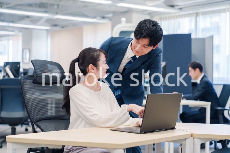 先輩社員から業務を教えてもらう新人の女性