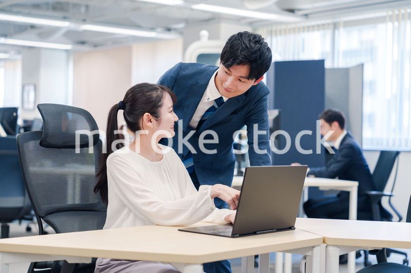 先輩社員から業務を教えてもらう新人の女性