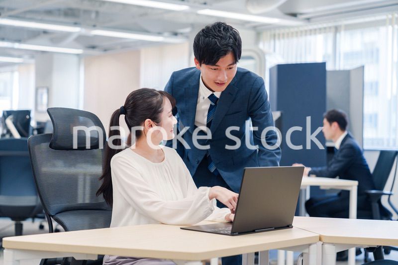 先輩社員から業務を教えてもらう新人の女性