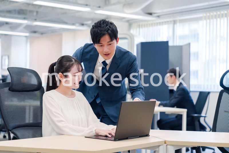 先輩社員から業務を教えてもらう新人の女性