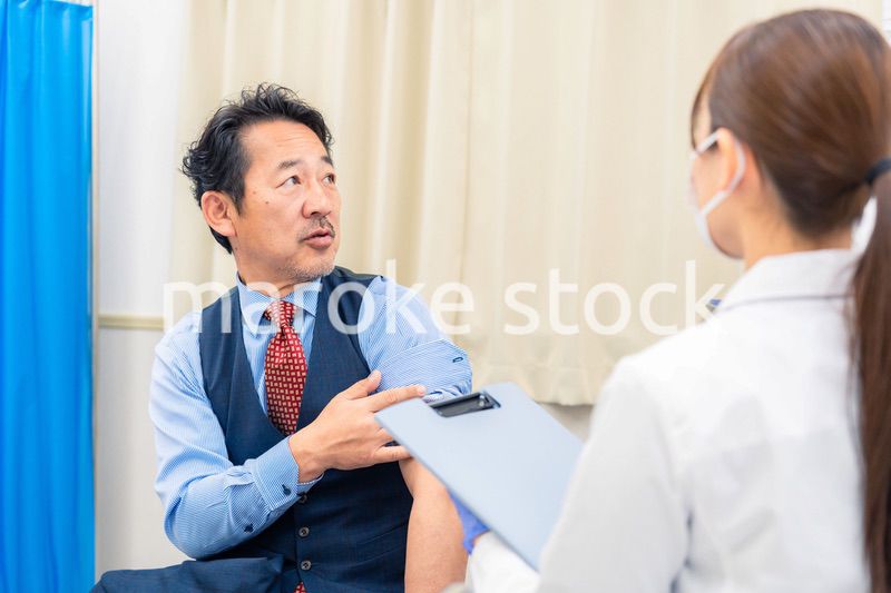 病院で男性患者の問診をする女性医師