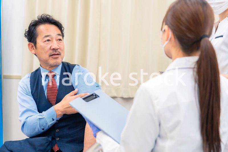 病院で男性患者の問診をする女性医師