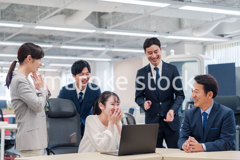 チームメンバーで非常ににこやかに仕事をするオフィスワーカー