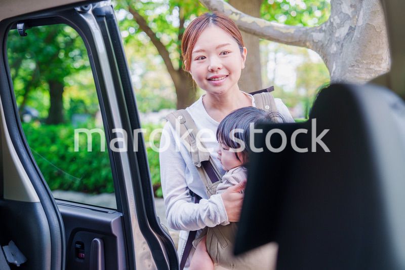 抱っこ紐で子供と一緒にタクシーに乗る女性