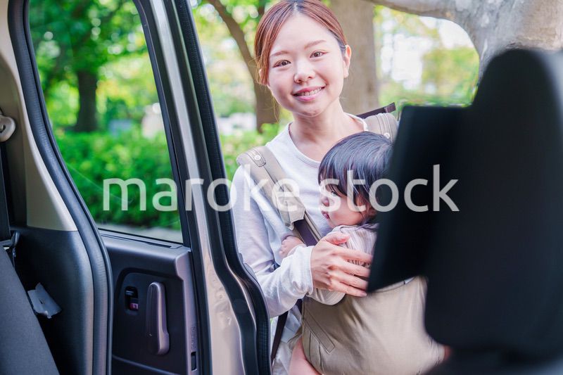 抱っこ紐で子供と一緒にタクシーに乗る女性