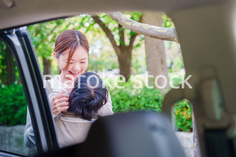 抱っこ紐で子供と一緒にタクシーに乗る女性