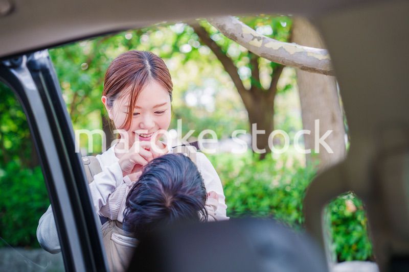 抱っこ紐で子供と一緒にタクシーに乗る女性