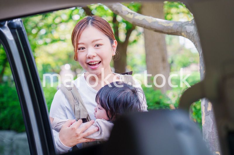 抱っこ紐で子供と一緒にタクシーに乗る女性