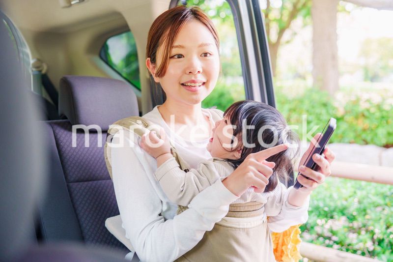 抱っこ紐で子供と一緒にタクシーに乗る女性