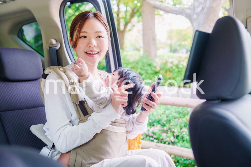 抱っこ紐で子供と一緒にタクシーに乗る女性