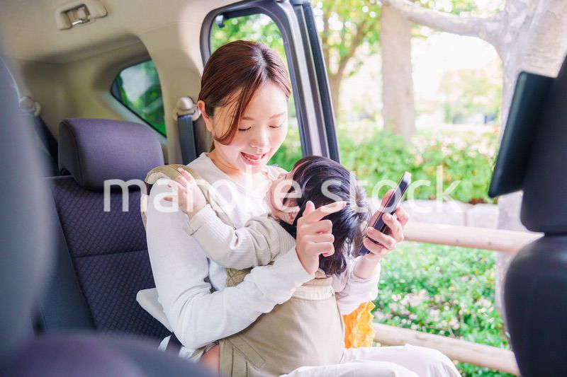 抱っこ紐で子供と一緒にタクシーに乗る女性