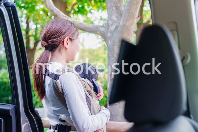 抱っこ紐で子供と一緒にタクシーに乗る女性