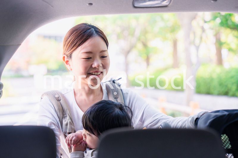 抱っこ紐をして車でお出かけをするお母さん