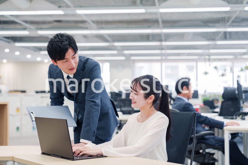 オフィスのデスクで打ち合わせをする男女のビジネスパーソン