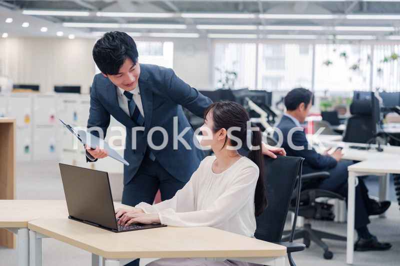 オフィスのデスクで打ち合わせをする男女のビジネスパーソン