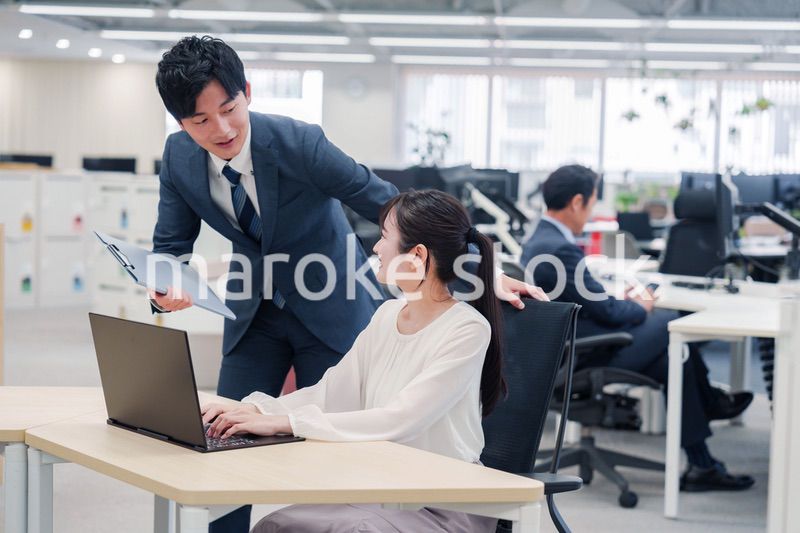 オフィスのデスクで打ち合わせをする男女のビジネスパーソン