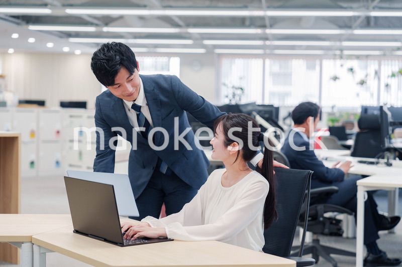 オフィスのデスクで打ち合わせをする男女のビジネスパーソン