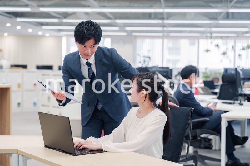 オフィスのデスクで打ち合わせをする男女のビジネスパーソン