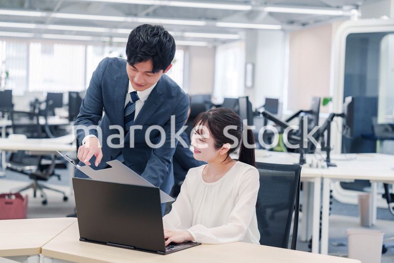 オフィスのデスクで打ち合わせをする男女のビジネスパーソン