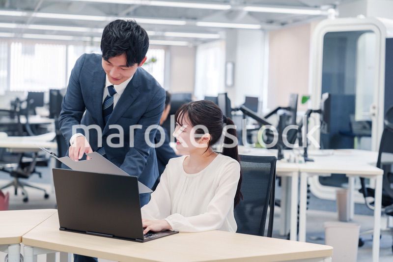 オフィスのデスクで打ち合わせをする男女のビジネスパーソン