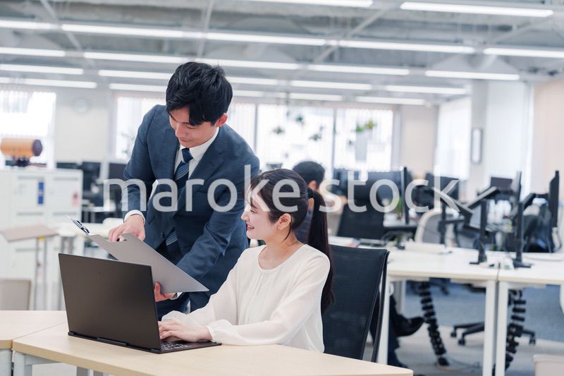 オフィスのデスクで打ち合わせをする男女のビジネスパーソン