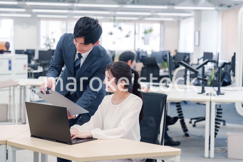 オフィスのデスクで打ち合わせをする男女のビジネスパーソン