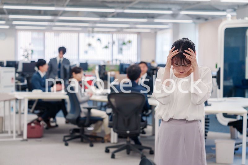 オフィスで頭を抱える女性従業員