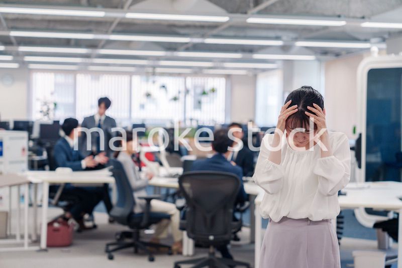 オフィスで頭を抱える女性従業員
