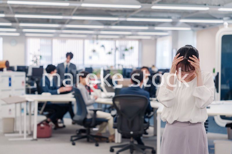 オフィスで頭を抱える女性従業員