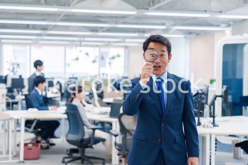 オフィスで虫眼鏡を使う中年のビジネスマン