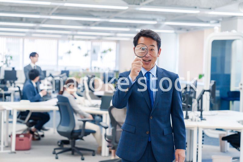 オフィスで虫眼鏡を使う中年のビジネスマン