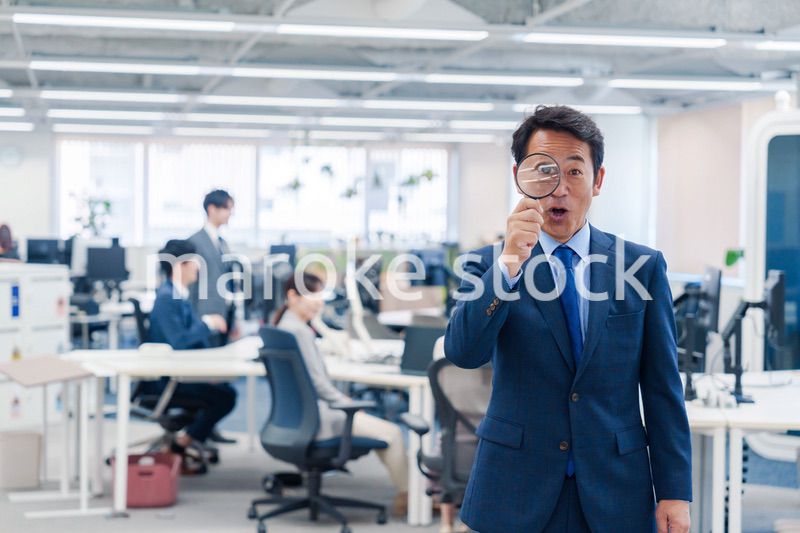 オフィスで虫眼鏡を使う中年のビジネスマン