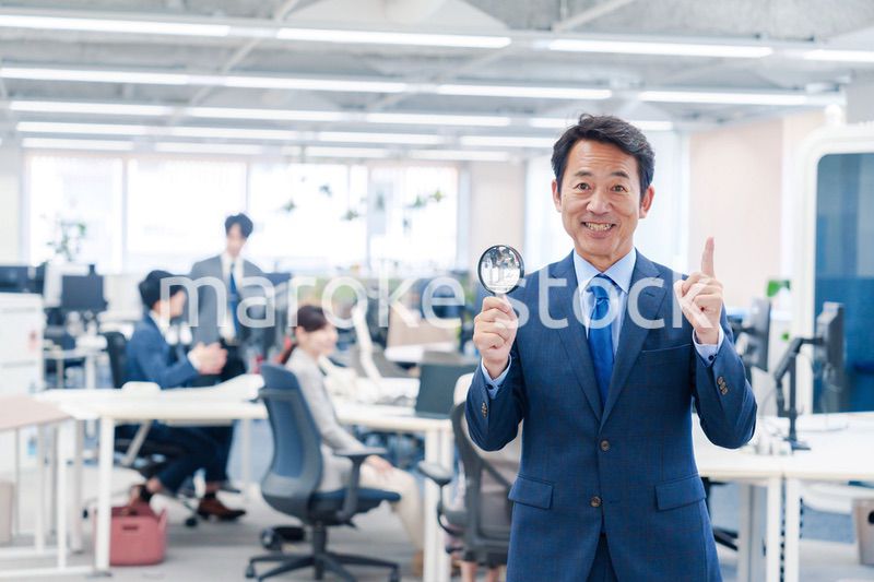 オフィスで虫眼鏡を使う中年のビジネスマン