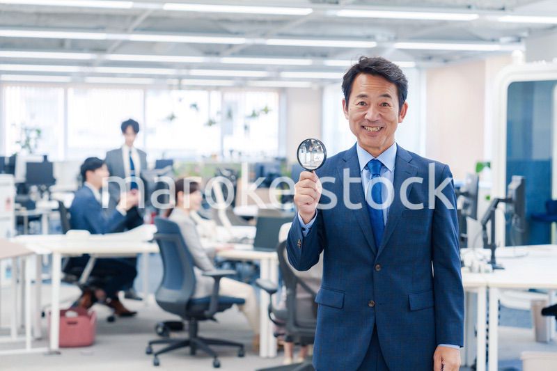オフィスで虫眼鏡を使う中年のビジネスマン