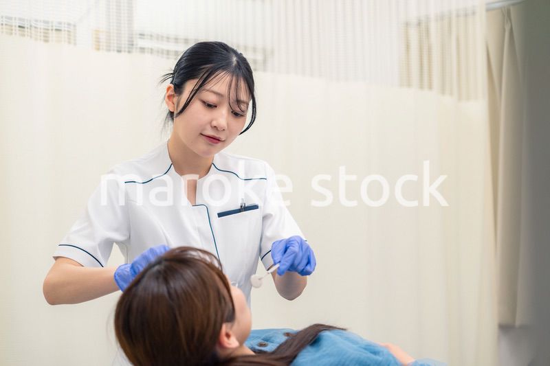 患者の歯のクリーニングをする歯科助手の女性