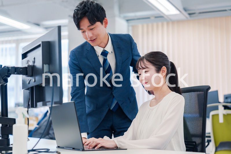 先輩に仕事を教えてもらう若い女性の会社員