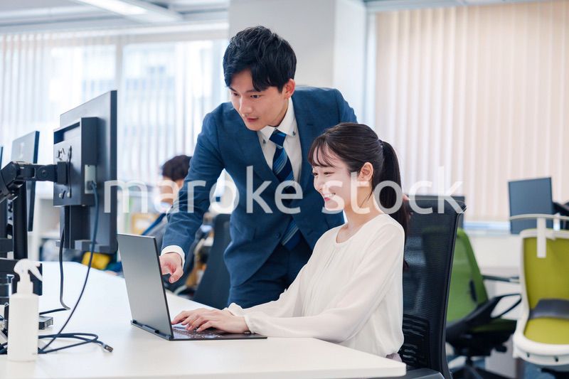 先輩に仕事を教えてもらう若い女性の会社員