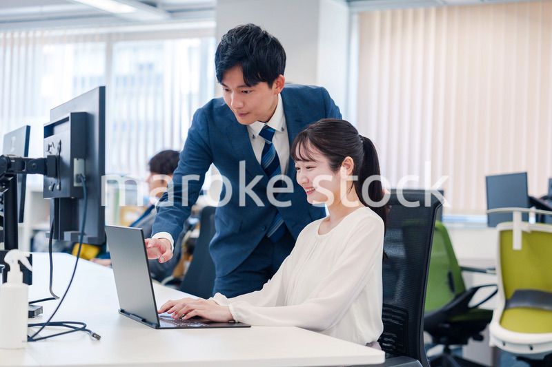 先輩に仕事を教えてもらう若い女性の会社員