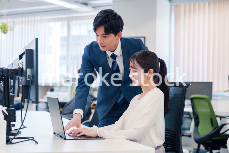 先輩に仕事を教えてもらう若い女性の会社員