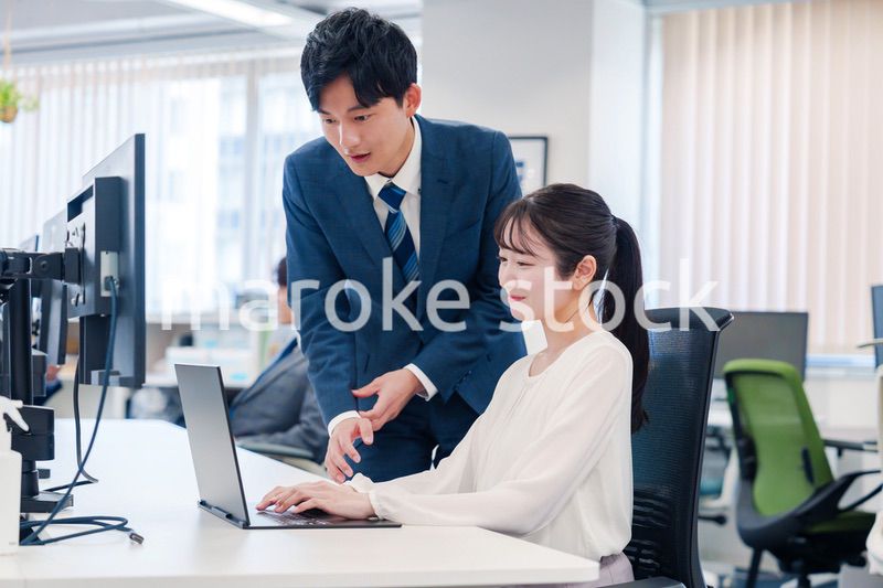 先輩に仕事を教えてもらう若い女性の会社員