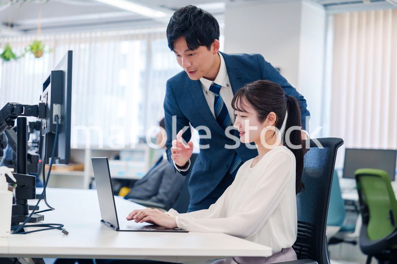 先輩に仕事を教えてもらう若い女性の会社員