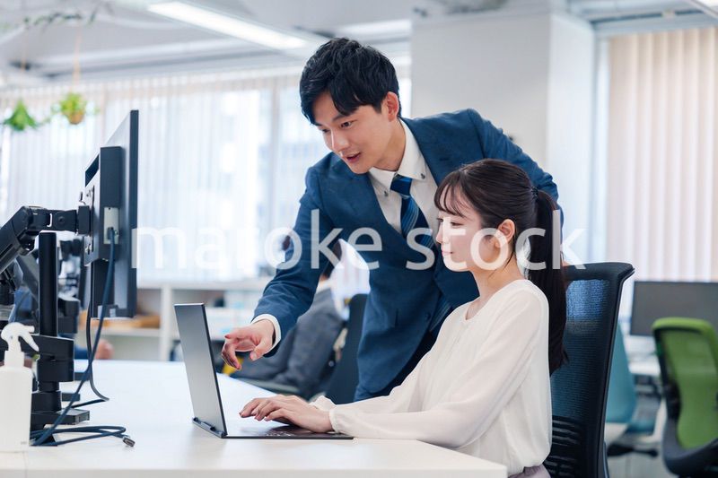 先輩に仕事を教えてもらう若い女性の会社員