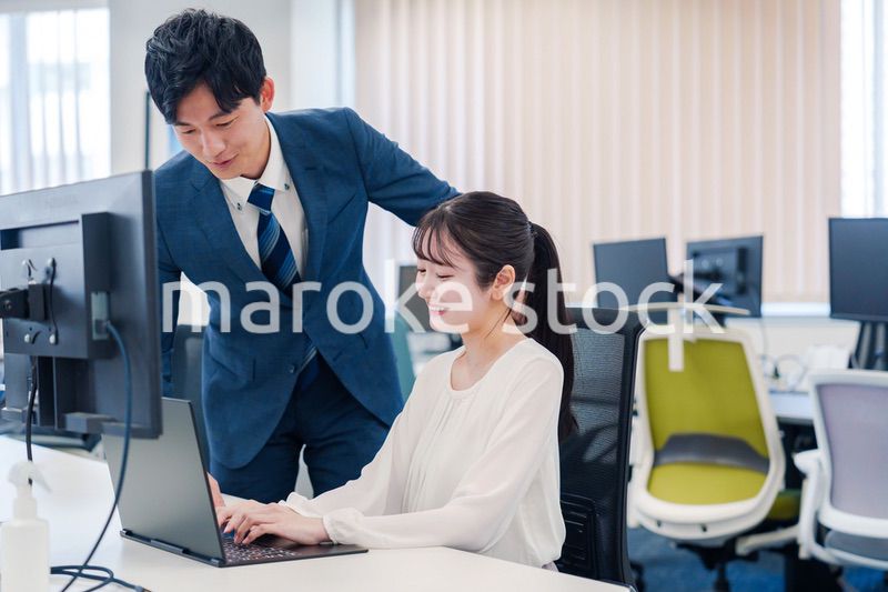 先輩に仕事を教えてもらう若い女性の会社員
